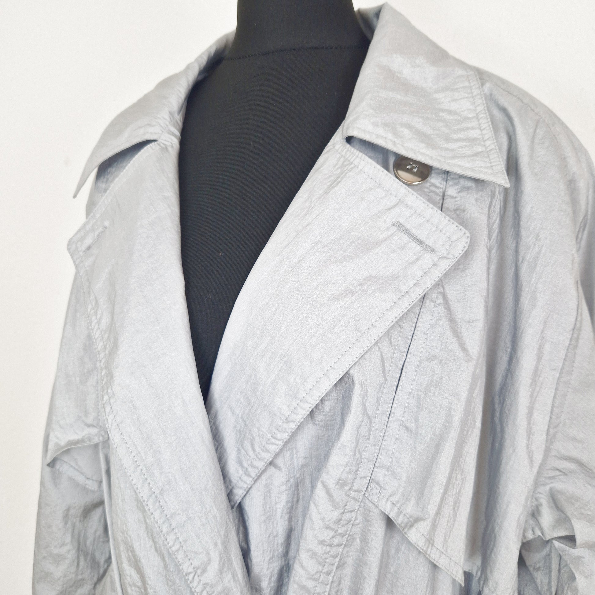 Einzigartiger und nachhaltiger Vintage Regenmantel in hellgrau. Unique and sustainable vintage raincoat in light grey. Close-up.