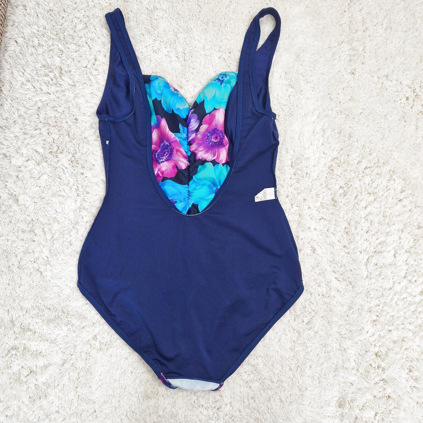 Einzigartiger und nachhaltiger Vintage Badeanzug in dunkelblau-violett-türkis mit Blumen. Unique and sustainable vintage swimsuit in darkblue-purple-turquois with flower. Back.