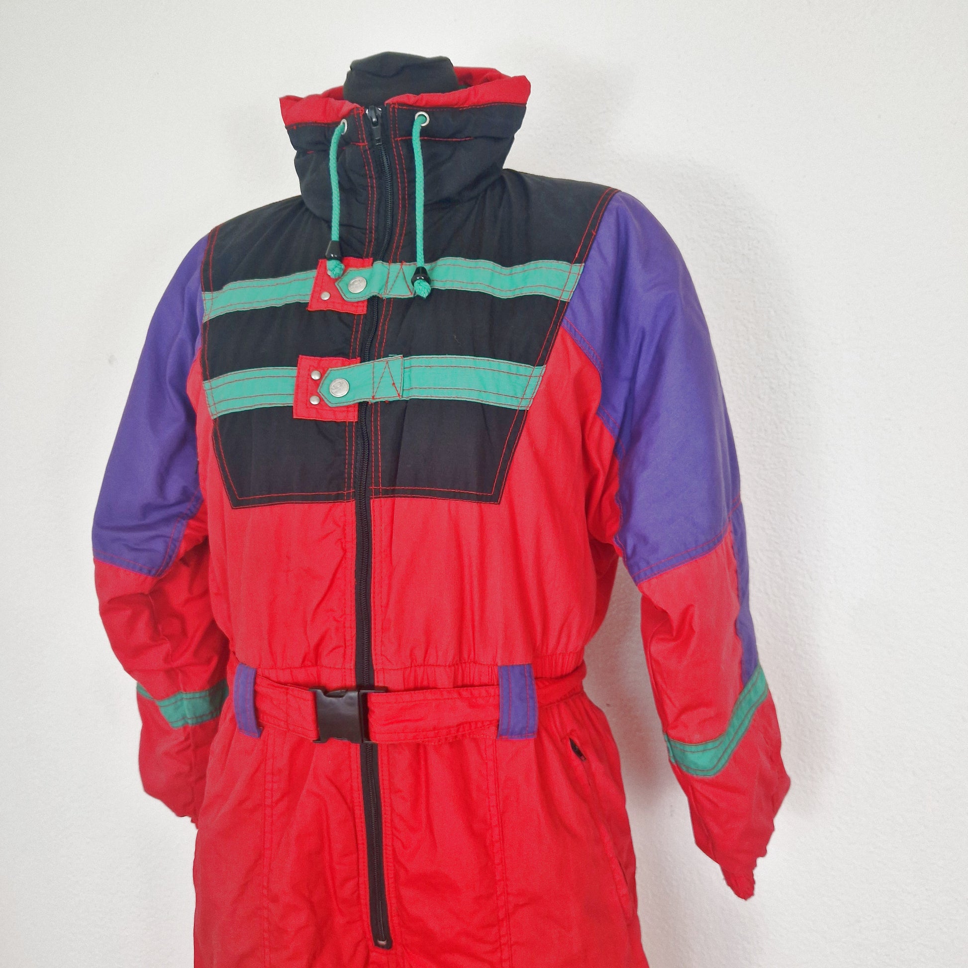 Einzigartiger und nachhaltiger Vintage Skianzug in rot-schwarz-grün mit Kapuze. Unique and sustainable vintage ski suit in red-black-green with hood. Close-up.