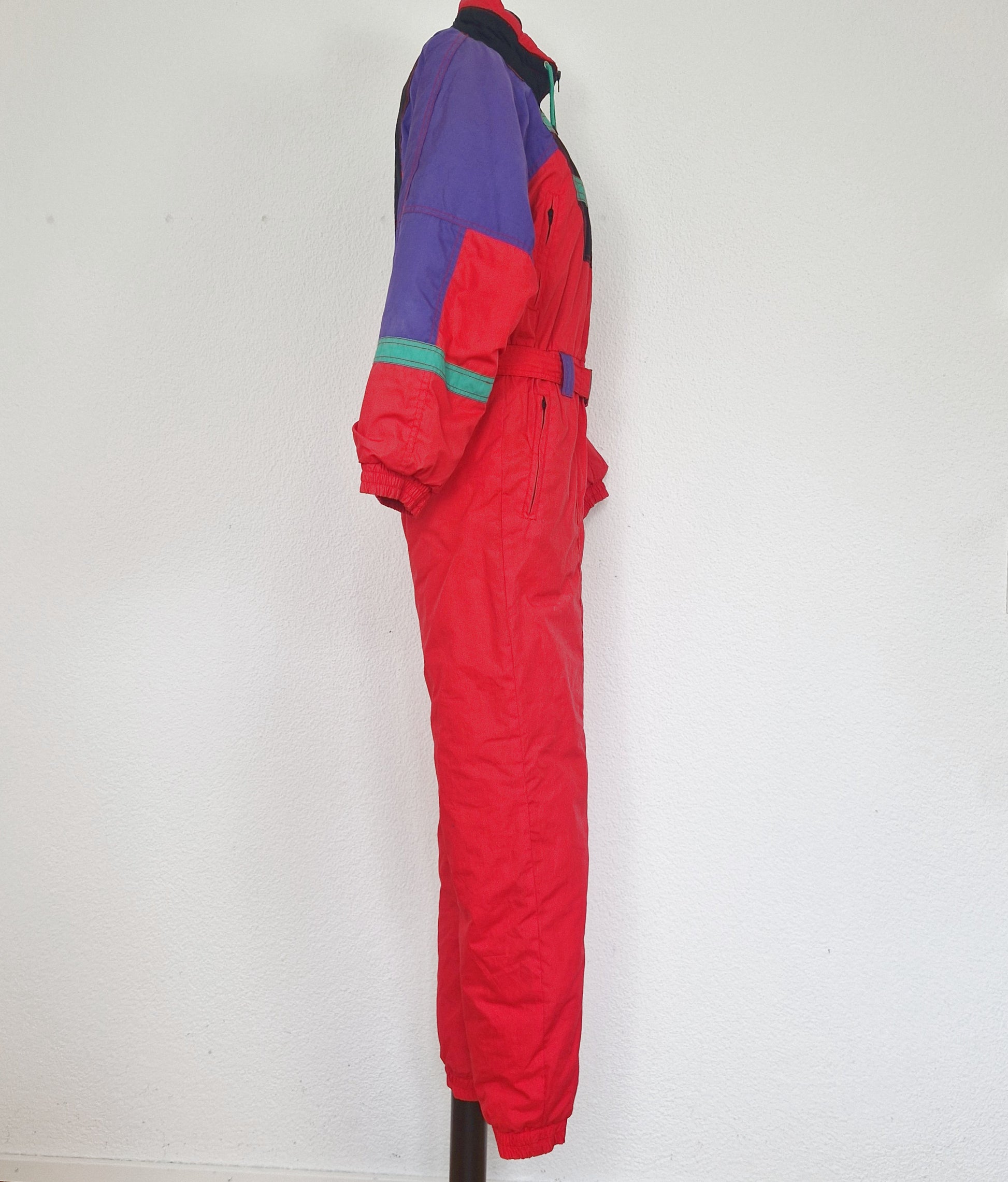 Einzigartiger und nachhaltiger Vintage Skianzug in rot-schwarz-grün mit Kapuze. Unique and sustainable vintage ski suit in red-black-green with hood. Side.