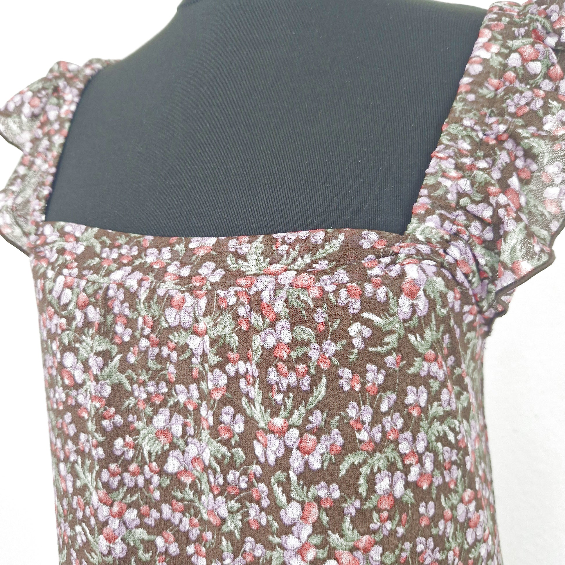 Einzigartiges und nachhaltiges Vintage Trägerkleid in braun-lila-rot mit Blumen und Rüschenärmeln. Close-up.