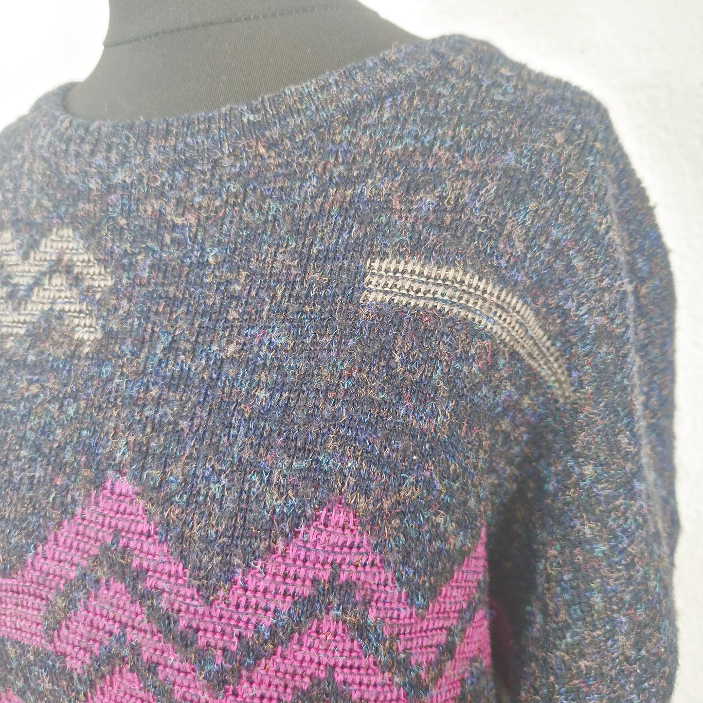 Einzigartiger und nachhaltiger Vintage Pulloverin anthrazit-pink-blau mit geometrischem Muster. Close-up.