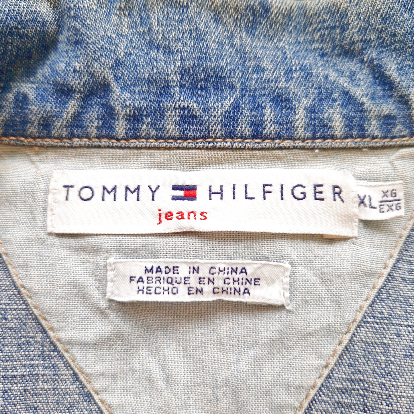 Einzigartige und nachhaltige Vintage Jeansjacke in blau von Tommy Hilfiger mit USA Fahne. Tag.